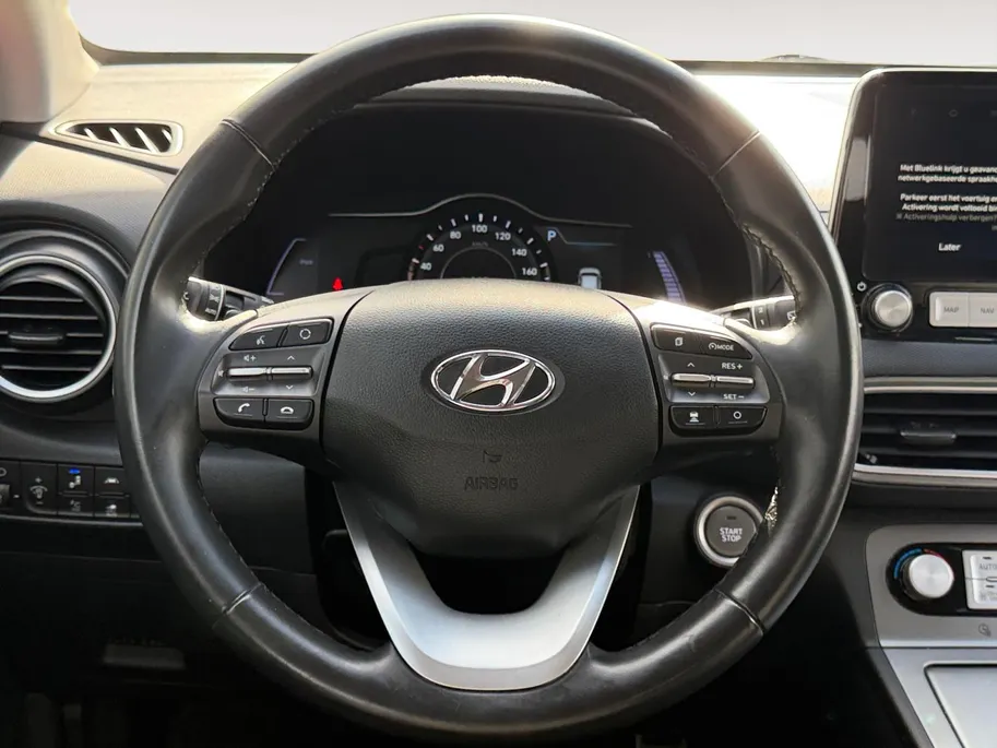 Hyundai Kona EV Fashion 64 kWh 204PK | Warmtepomp | SOH 100 % | Navigatie | Apple Carplay & Android Auto | Adaptive cruise control | Climate control | Head-up display | Parkeersensoren achter | Trekhaak |